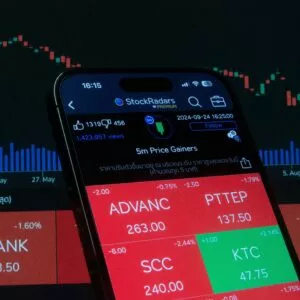 Mobile screen displaying stock market analysis with financial charts in the background.